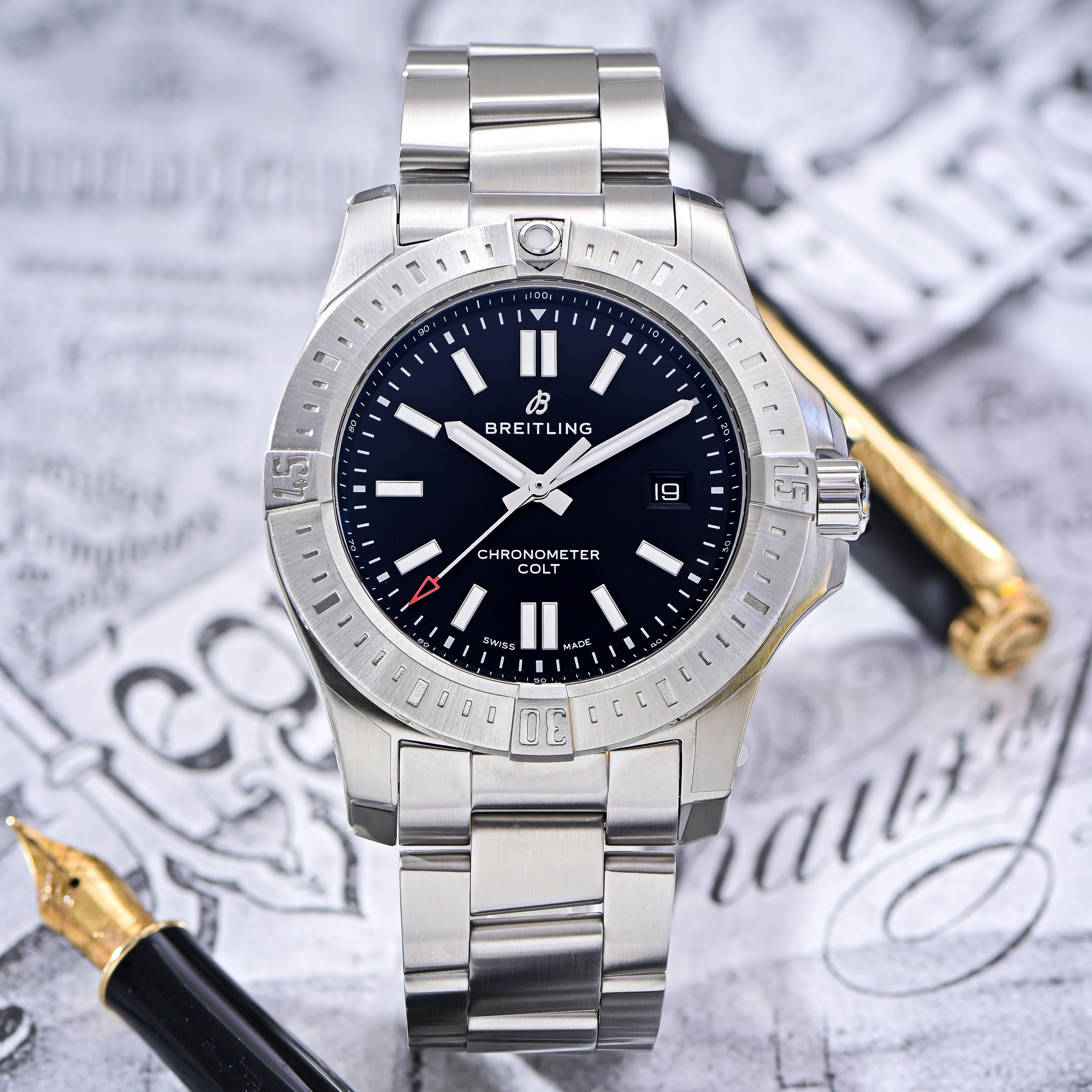 Stainless Steel Breitling Colt, Black Index Dial with Stainless Steel Bracelet on a Black and White Background Beside an Open Felt Tip Pen
