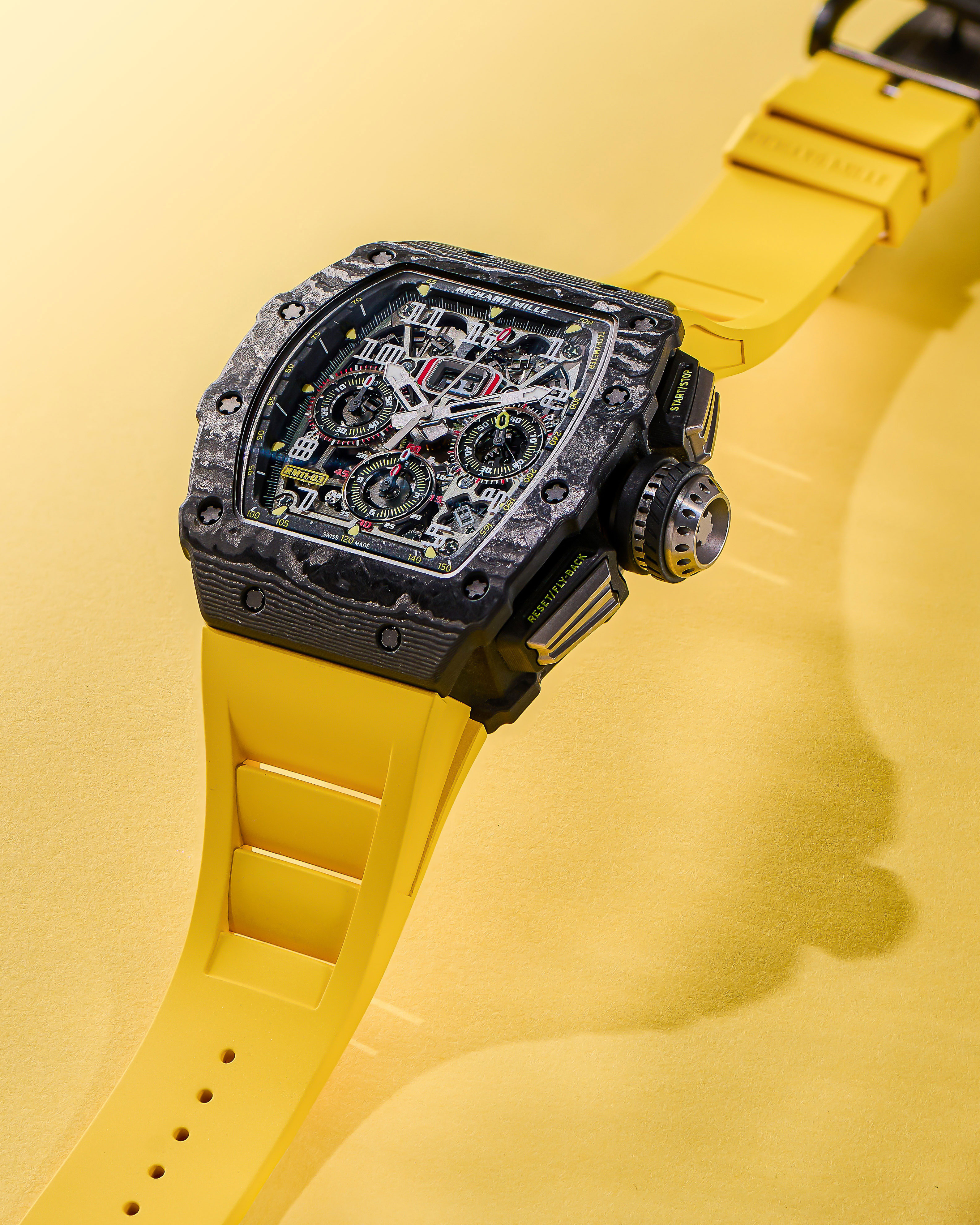 Carbon Bezel with Skeleton Dial and Neon Yellow Rubber Strap Lying on a Yellow Background