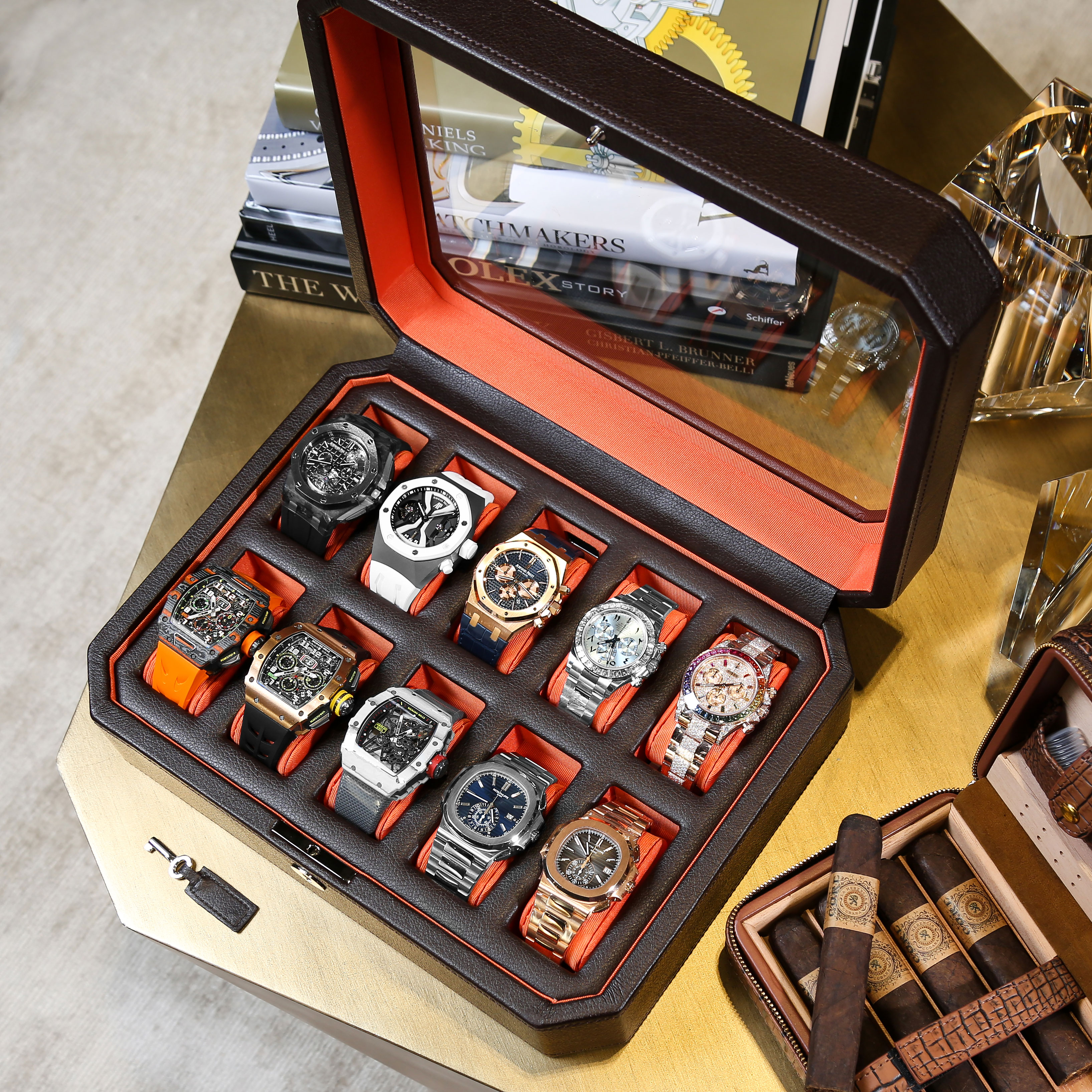 Black Leather Watch Box Filled with Ten Luxury Timepieces that Include Rolex, Audemars Piguet, Patek Philippe, and Richard Mille, Sitting on a Tabletop Beside a Case of Cigars