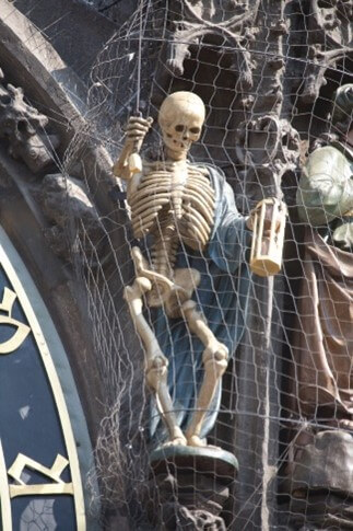 Skeleton Holds a Lantern in its Left Hand and a Sword in its Right, Sitting on the Left Side of The Prague Astronomical Clock