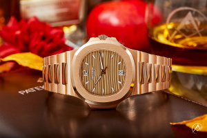 Patek Philippe Nautilus watch in rose gold on autumn themed background with Avi & Co. logo
