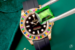 Green tsavorite in jewelry tweezers in front of Rolex watch