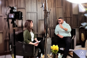 Tobi Sigona sits across from Avi Hiaeve, CEO and Founder of Avi & Co., in their Showroom in NYC surrounded by Lights and Cameras