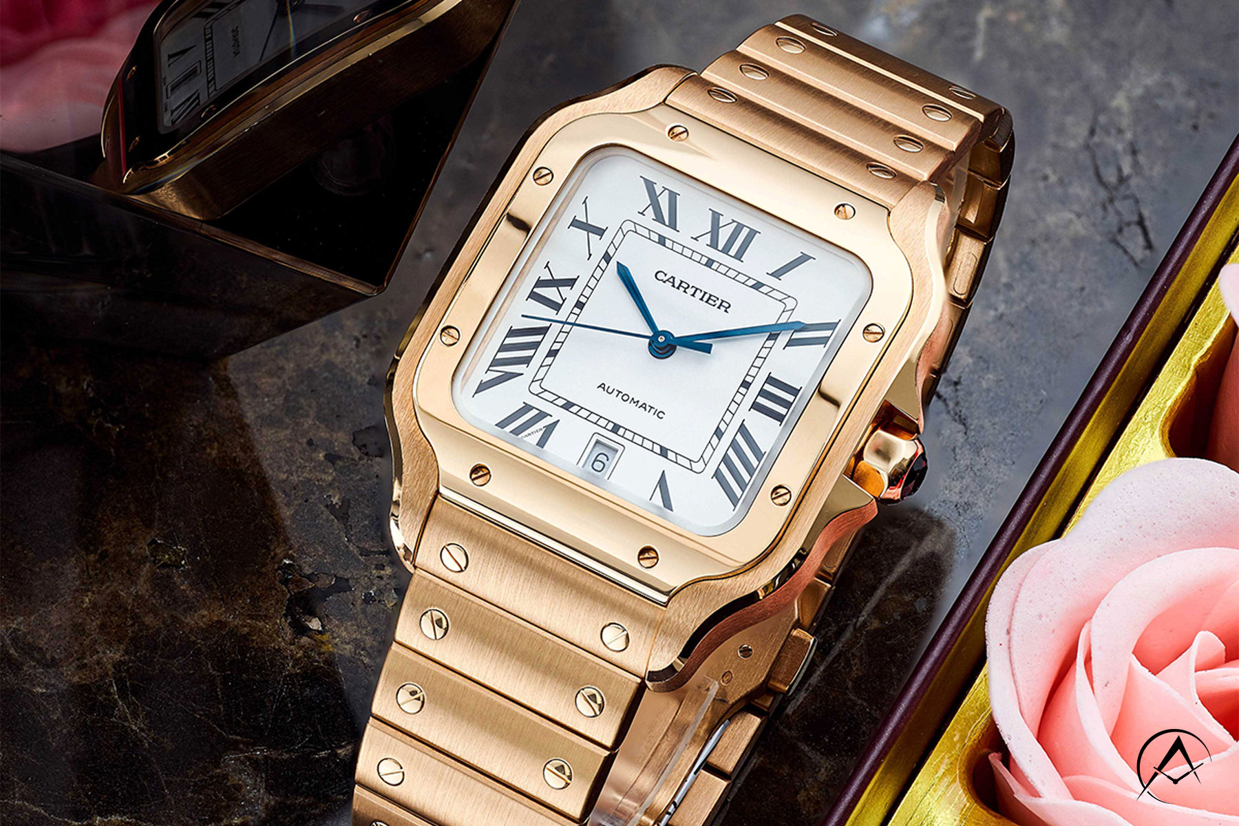 Gold Cartier Timepiece with White Dial and Black Roman Numerals Sitting on a C-Ring on a Black Marble Table Flanking Pink Roses.