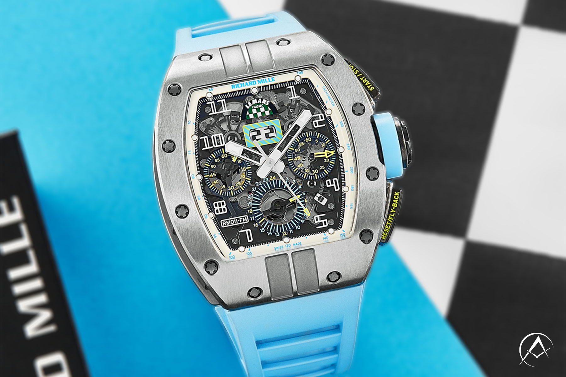 Richard Mille Timepiece with Openworked Dial and Light Blue Rubber Strap on a Light Blue, Black, and White Background.