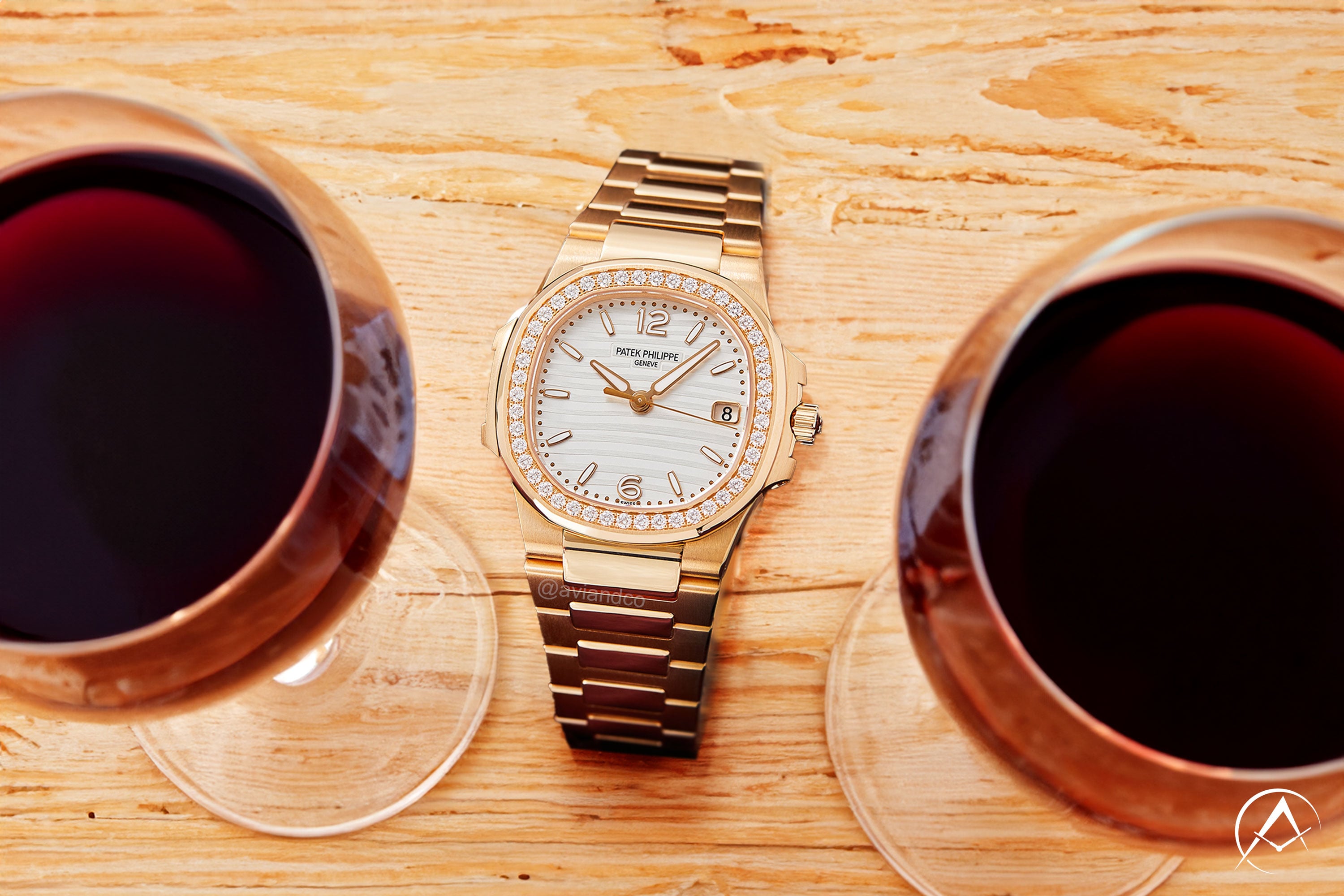 Patek Philippe Nautilus watch 18K rose gold with diamond bezel, 35 mm case, between two glasses of red wine on light wood table
