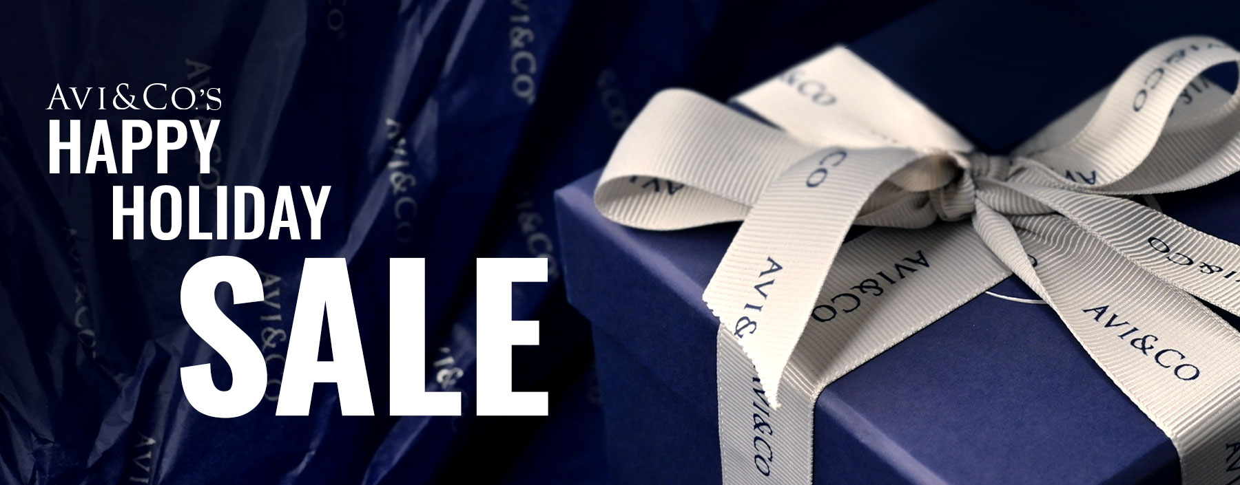 Blue Box with White Avi & Co. Bow on Top with the Words 'Avi & Co.'s Happy Holiday Sale' Displayed.