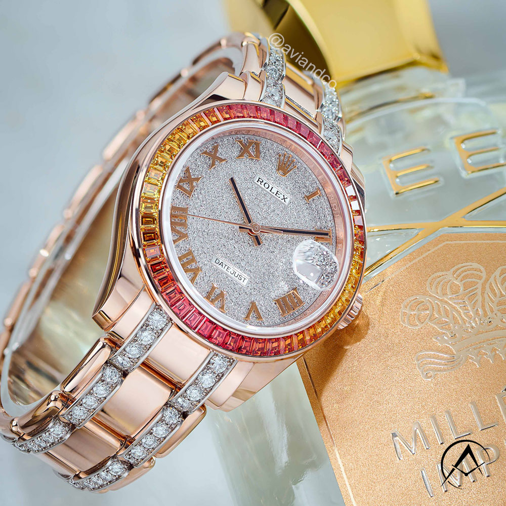 18K Everose Gold Timepiece with Yellow and Orange Sapphire Bezel, Date Function, and Automatic Movement Displayed on a Clear C-Ring.