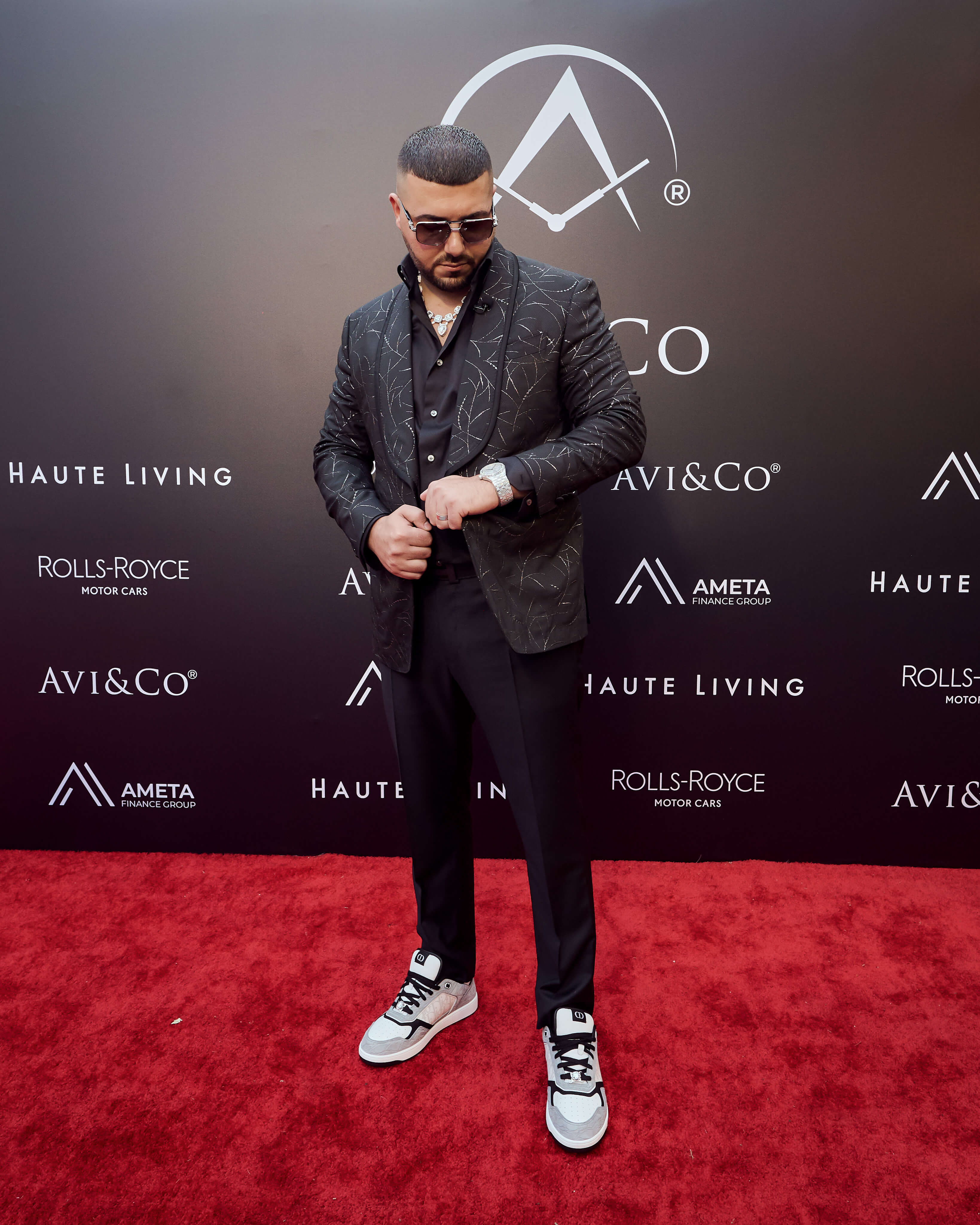 Man Wearing Diamond-Pave Luxury Timepiece, Black Suit, and The Crown Chain Diamond Necklace at the Avi & Co.’ Miami Grand Opening.