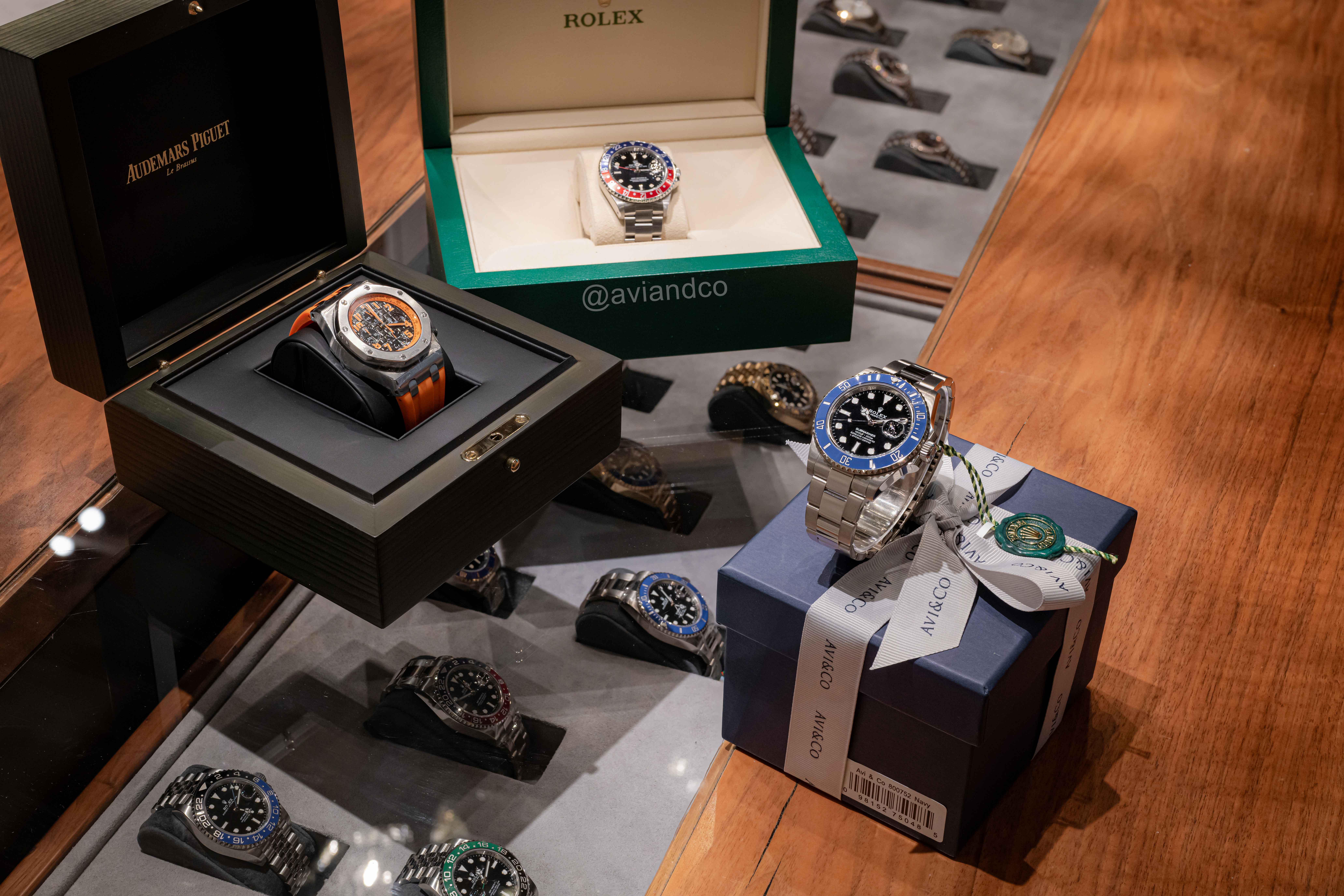 Audemars Piguet, Rolex Pepsi, and Rolex Submariner in Their Respective Boxes Displayed Over Additional Rolex Watches.