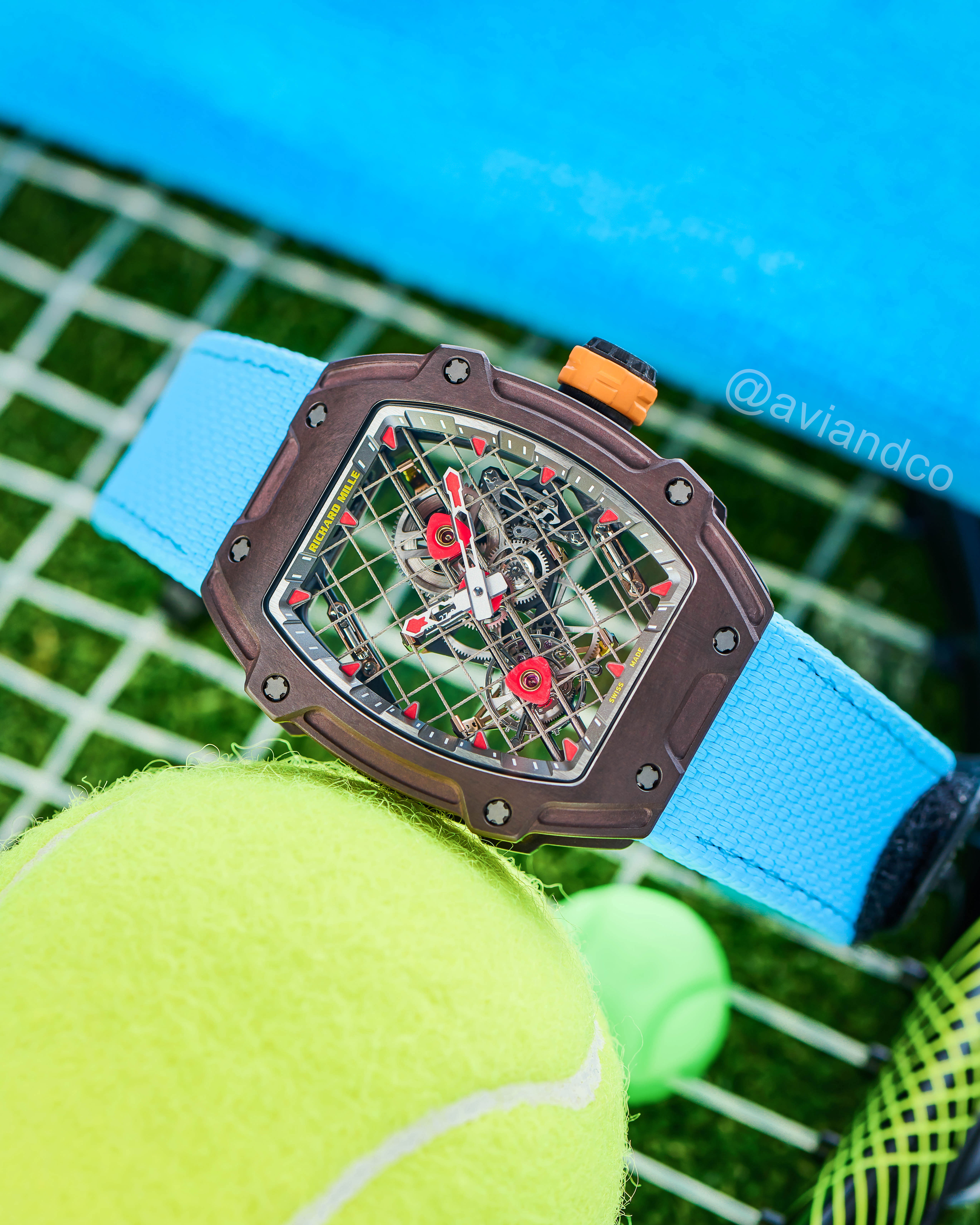 Skeleton Dial Timepiece with Blue Bracelet Lying Against a Tennis Ball.
