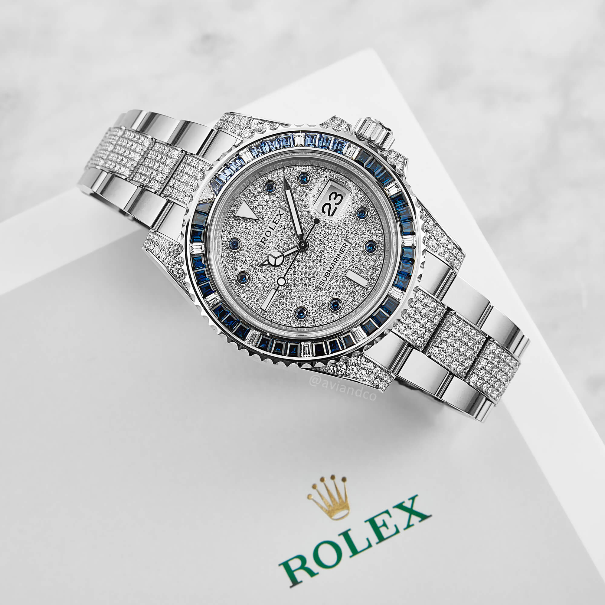 18L White Gold 40 mm Timepiece Set with Diamonds and Sapphires with an Automatic Movement and Date Function on a White Background, a Perfect Example of Water Resistance in a Rolex Watch.