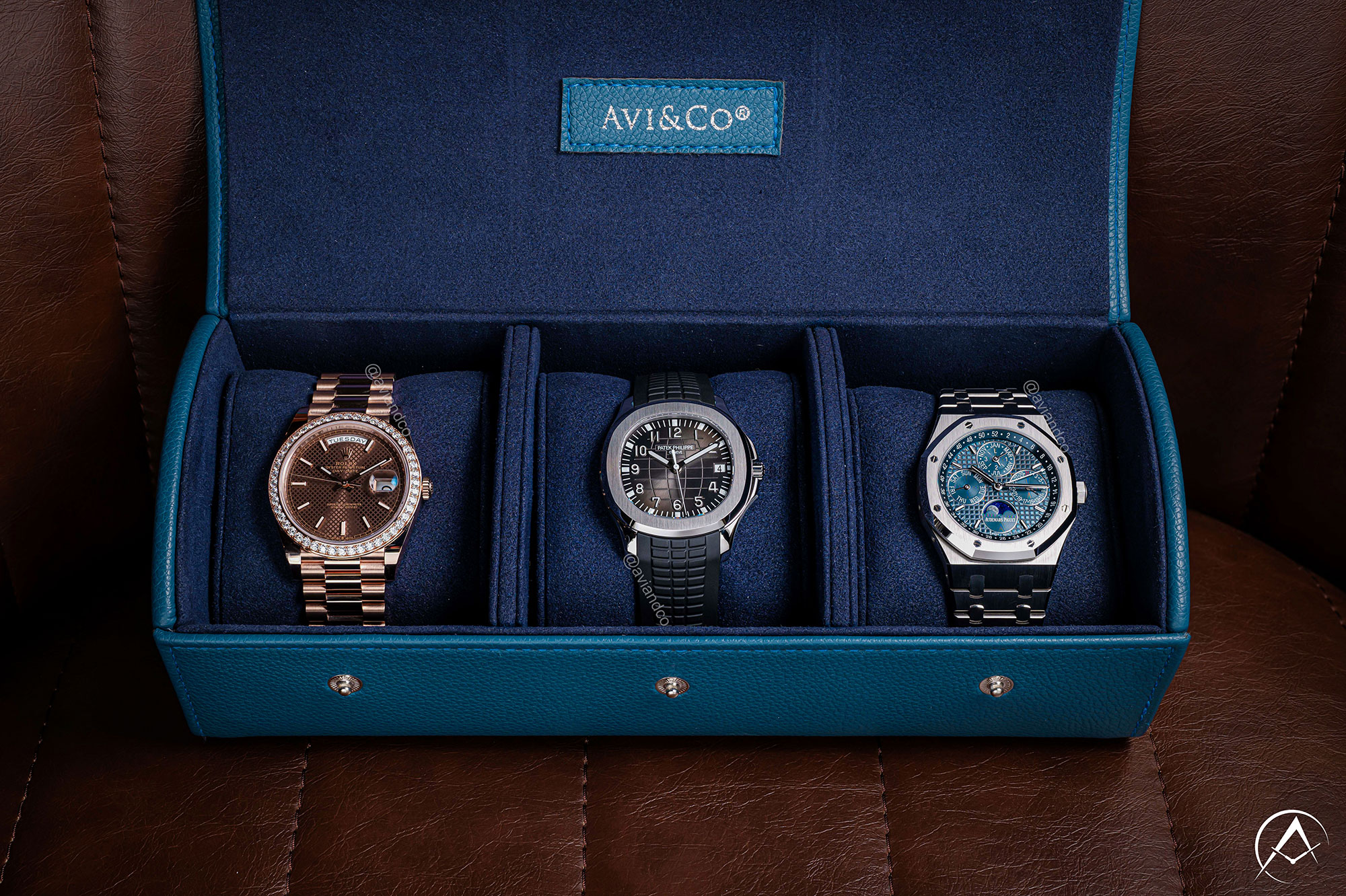 Three Luxury Watches Displayed in Navy Avi & Co. Watch Roll. From Left to Right: 18K Rose Gold Chocolate Diamond Bezel, Stainless Steel Black Arabic Dial, and Stainless Steel Blue Dial Chronograph, all with Medium Case Diameters.