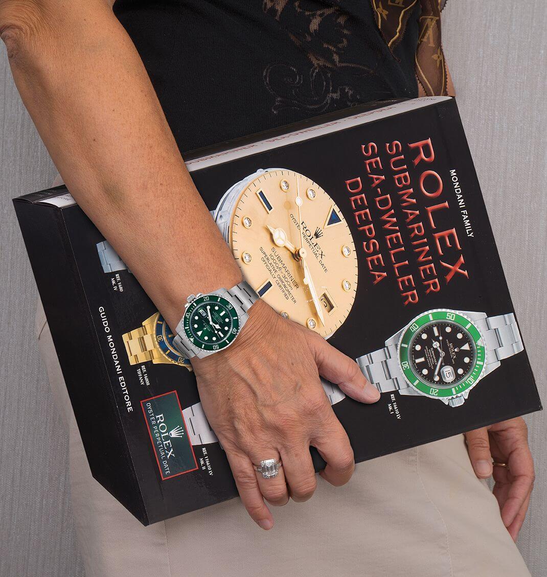 Giorgia Mondani wears a Rolex Hulk and Diamond Ring while Holding her book Rolex Submariner Sea-Dweller Deepsea.