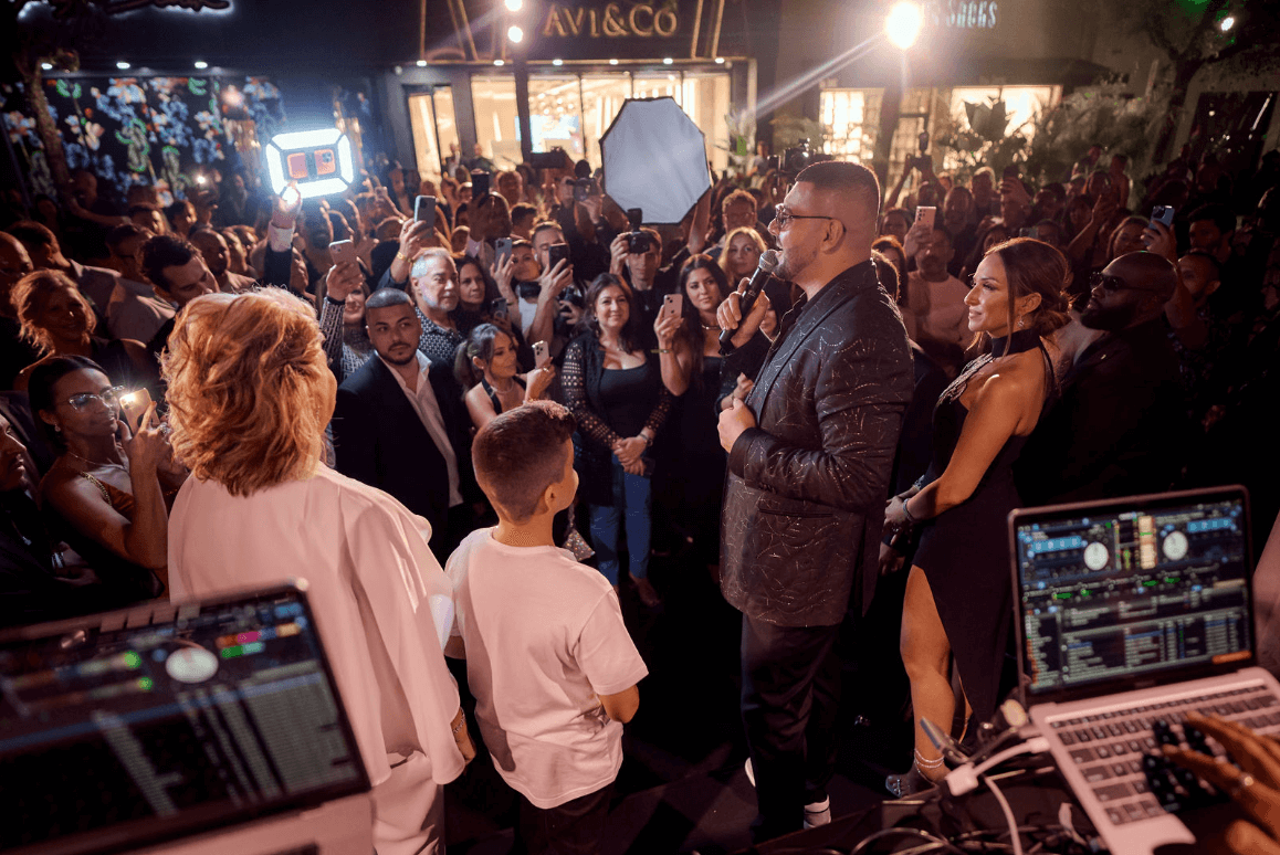Avi Hiaeve Stands on Stage with His Family Giving a Speech in Front of 1,000 Guests Outside of His Miami Boutique.