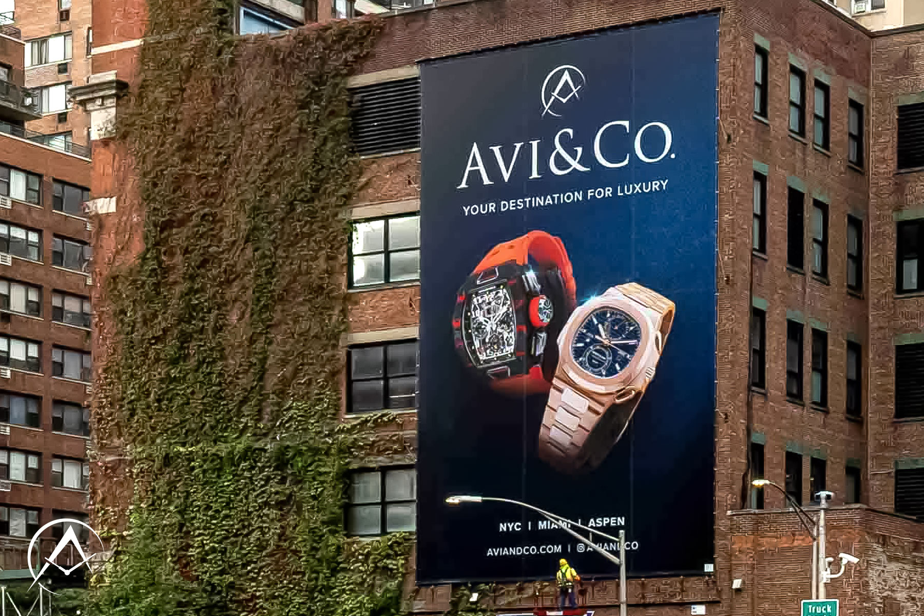 A Billboard in Front of a Building with the Avi & Co. Logo, the McLaren Richard Mille Watch, and a Patek Philippe Watch Advertising our Boutique in The Diamond District.