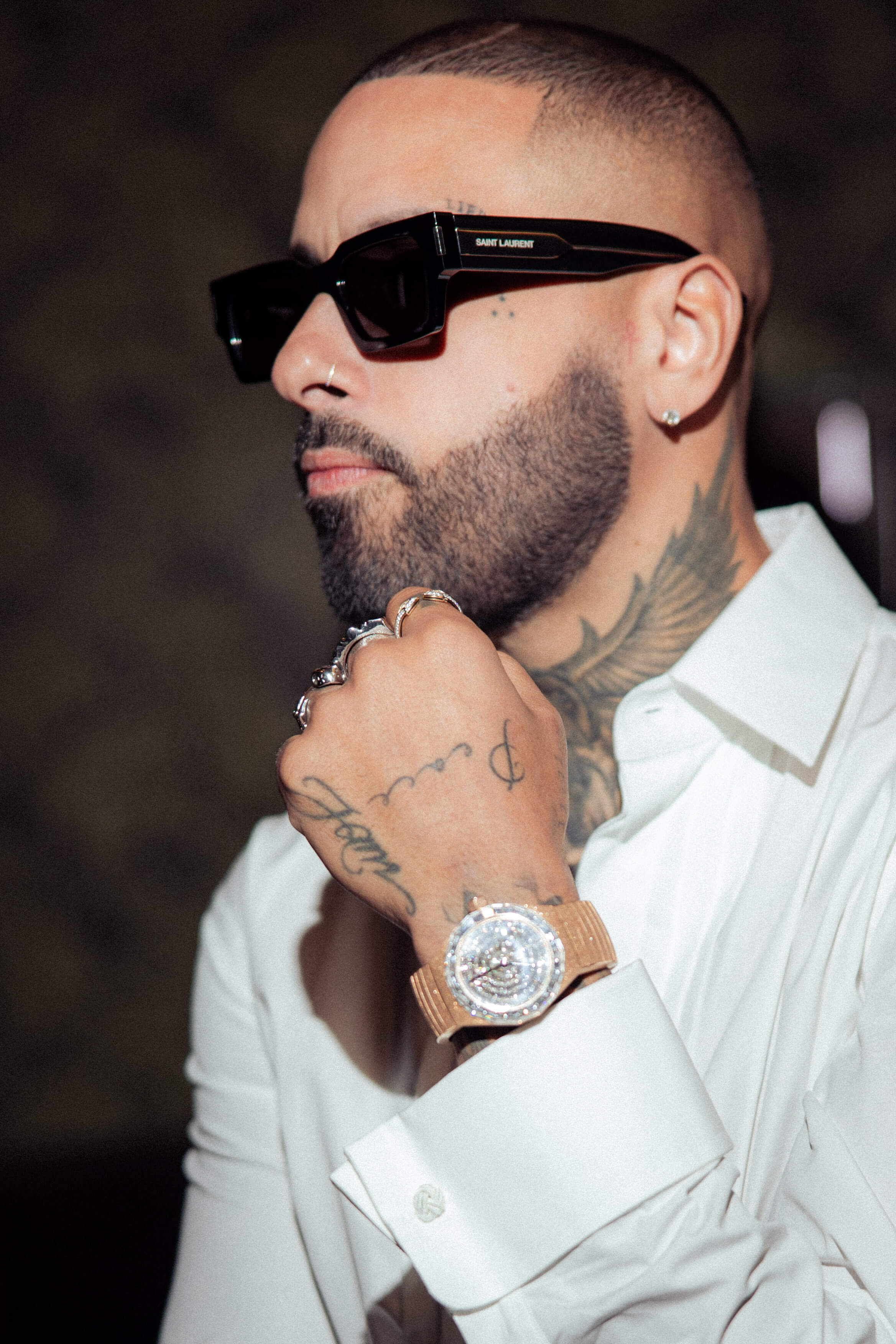 American Singer Wearing White Button-Down Shirt, Saint Laurent Sunglasses, and 40 mm Limited Edition Avi & Co. Timepiece from The Frosted Collection.