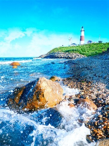 A Photograph of the Ocean in Long Island Overlooking a White and Red Lighthouse.