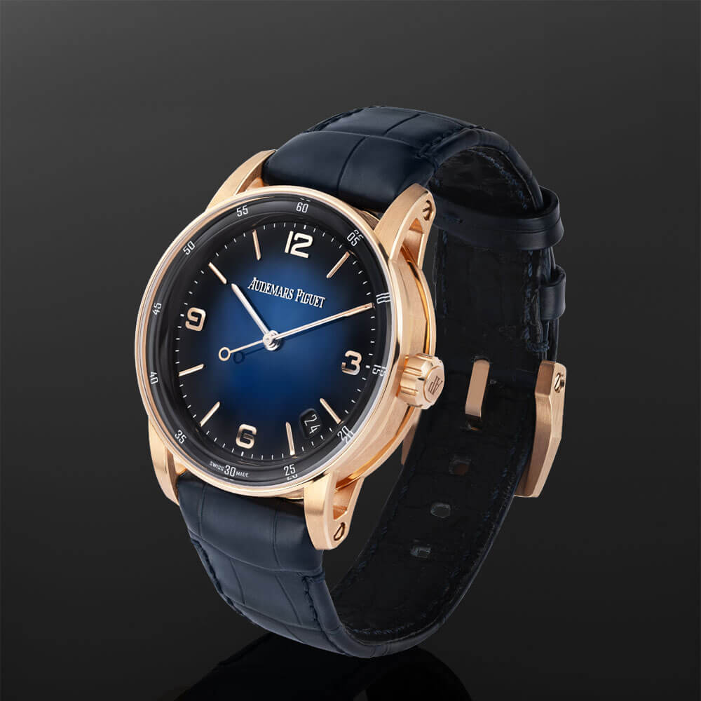 Rose Gold Audemars Piguet Code 11.59 Timepiece with Blue Dial and Leather Bracelet Displayed on a C-Ring with a Black Background.