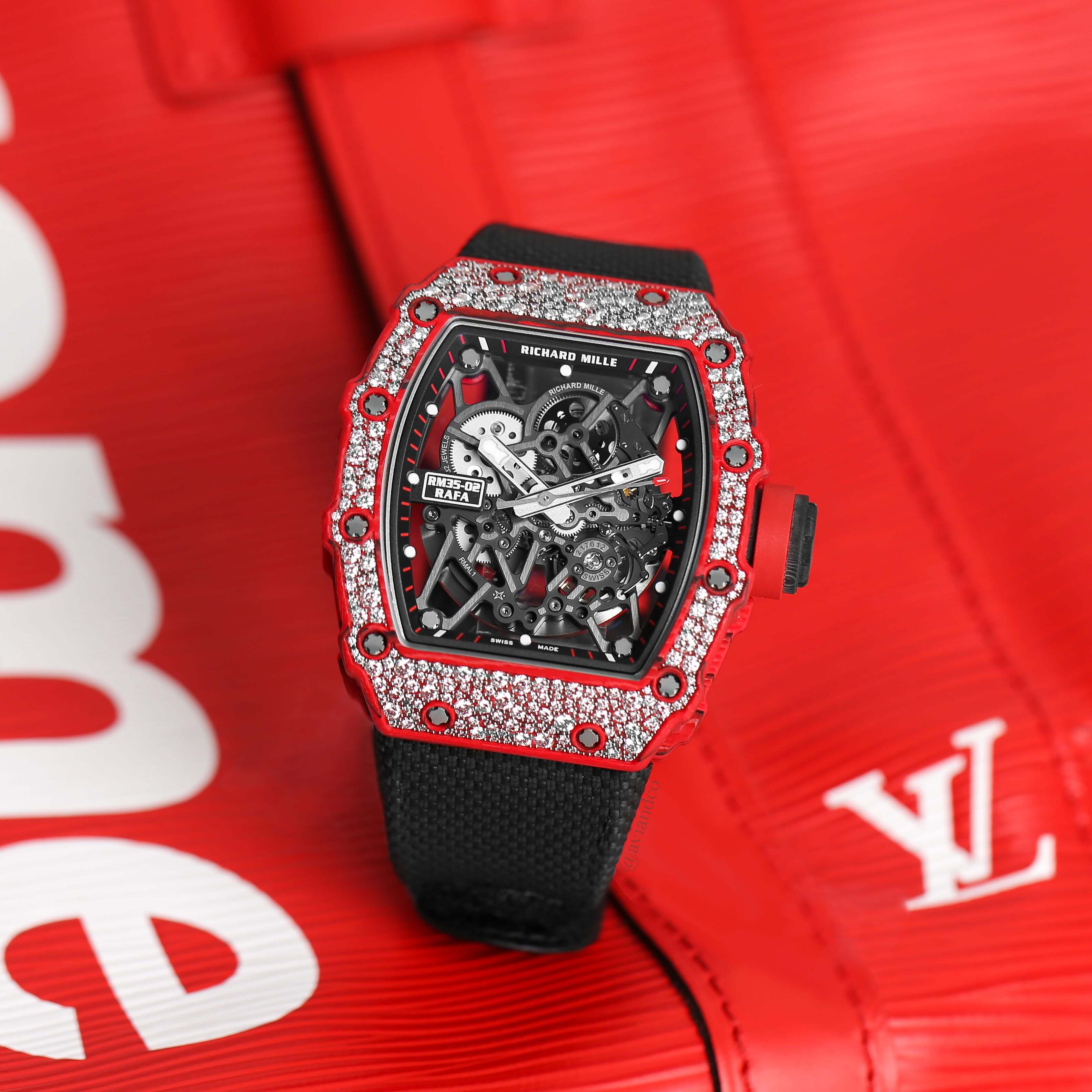 Red Diamond-Pave Bezel Timepiece with Openworked Dial and Black Rubber Strap on a Red Louis Vuitton Background.