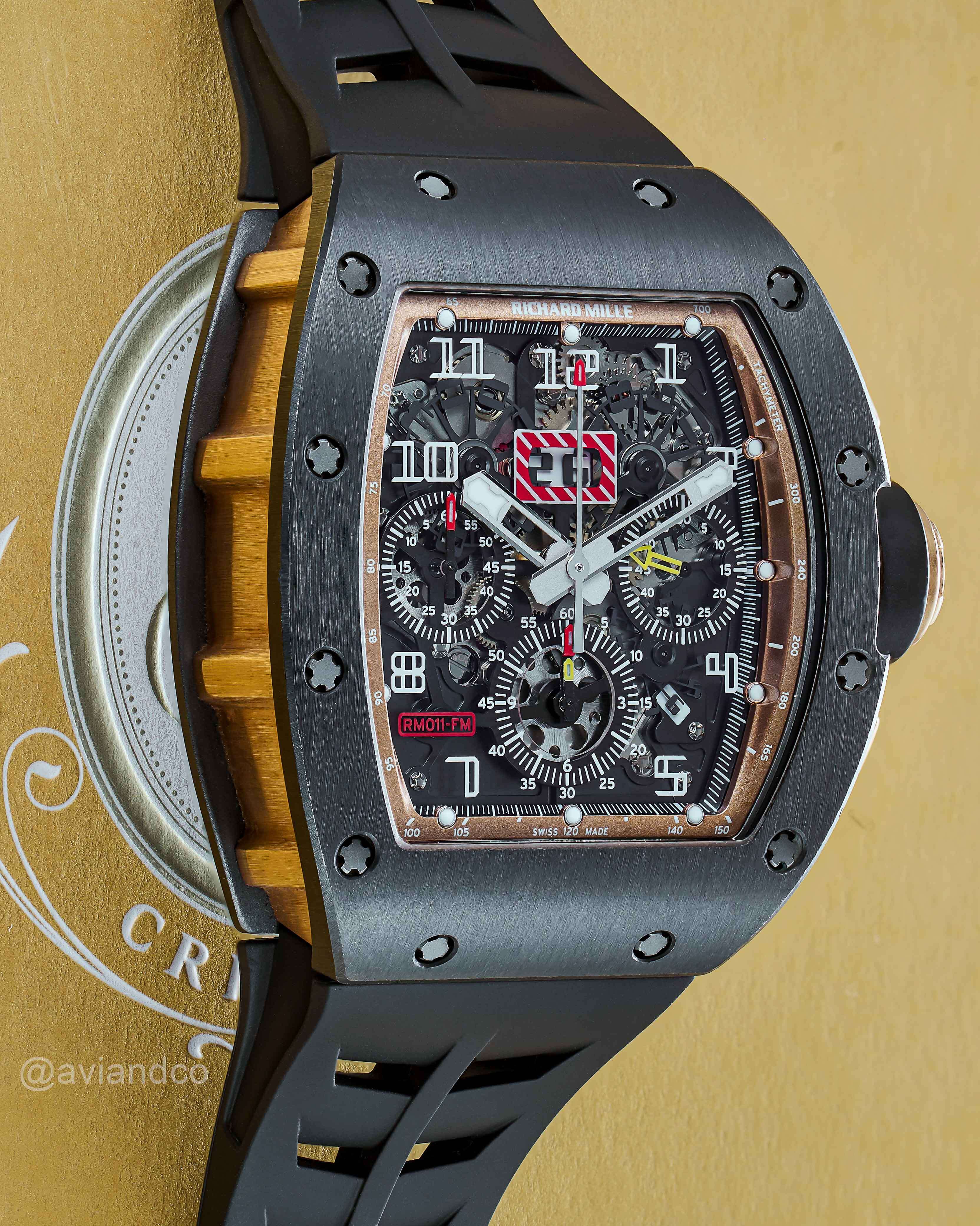 Felipe Massa x Richard Mille Partnership 011 Black Openworked Timepiece with Black Rubber Strap Laying Out on a Beige Background.