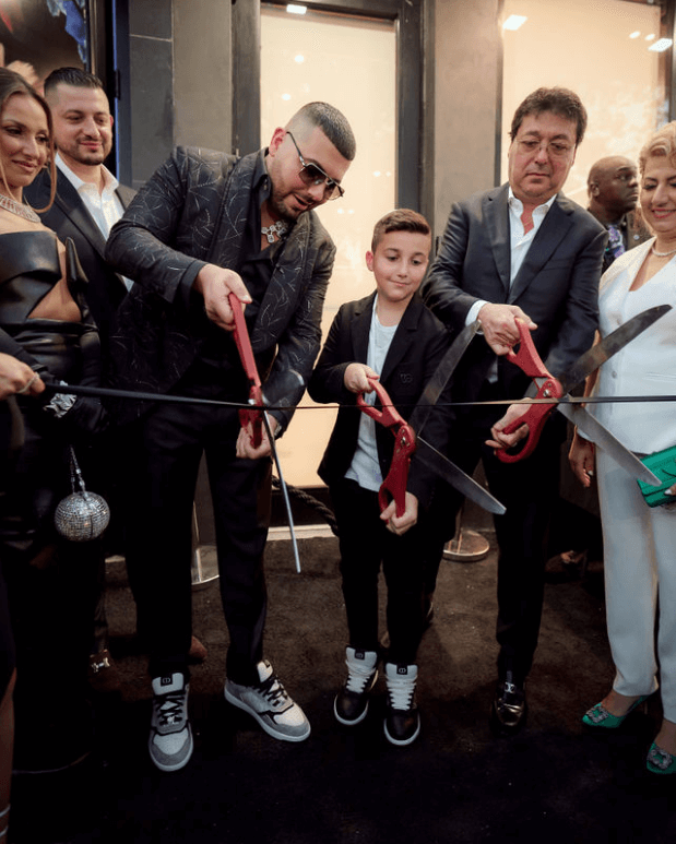Avi, His Son, and His Father Hold Large Scissors with Red Handles About to Cut the Ribbon in Front of Avi & Co.’s Miami Boutique in the Design District.