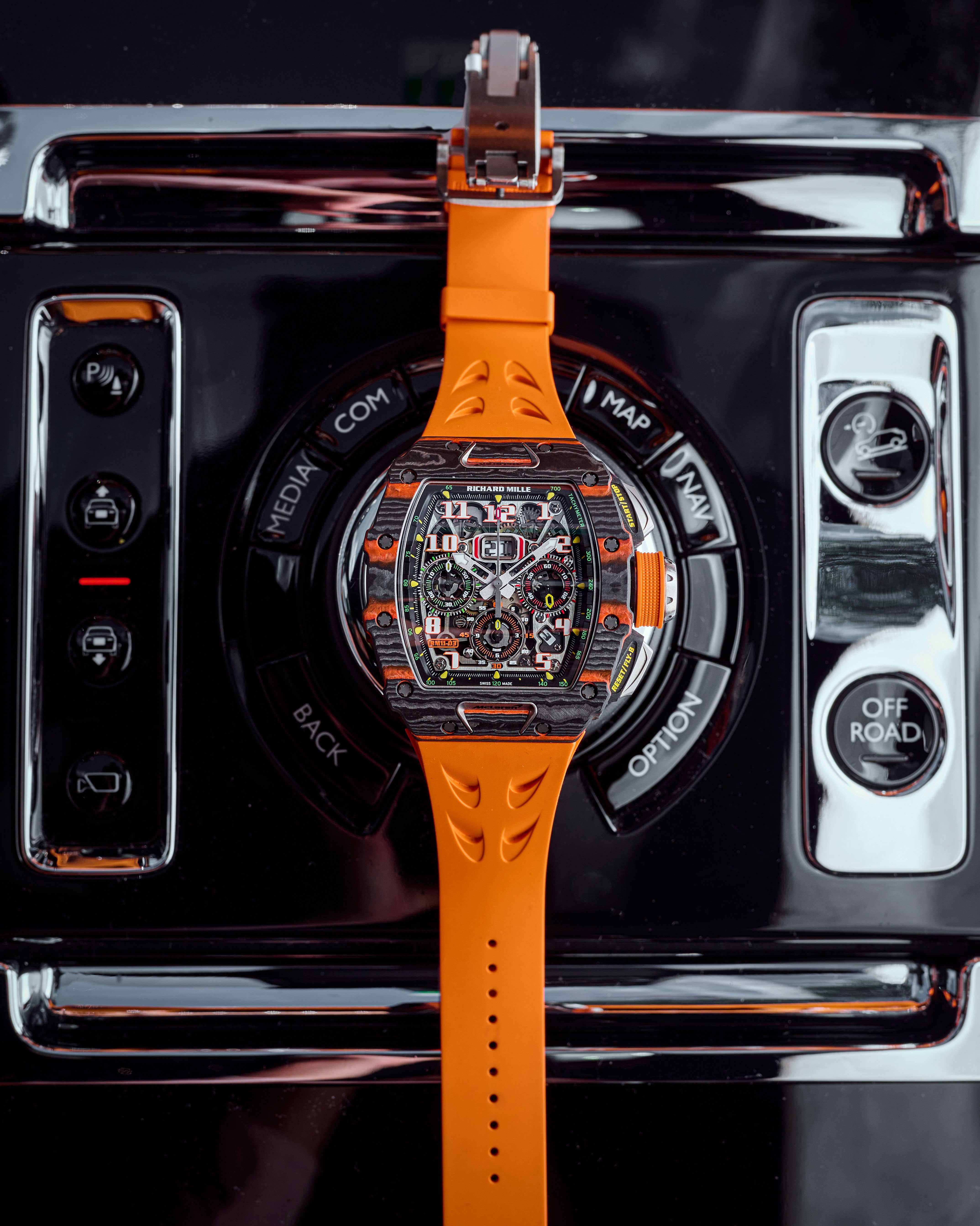 Carbon 44 mm Timepiece Assembled with Quartz TPT Bezel and Orange Rubber Strap Lying Out Inside of a Car.