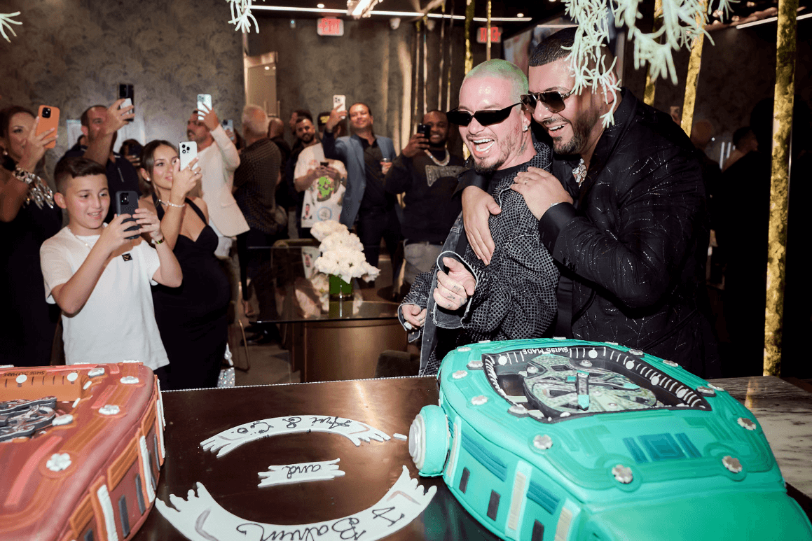 Avi Hiaeve Hugs J Balvin in Front of Two Richard Mille Shaped Cakes While Guests Take Photos and Videos.