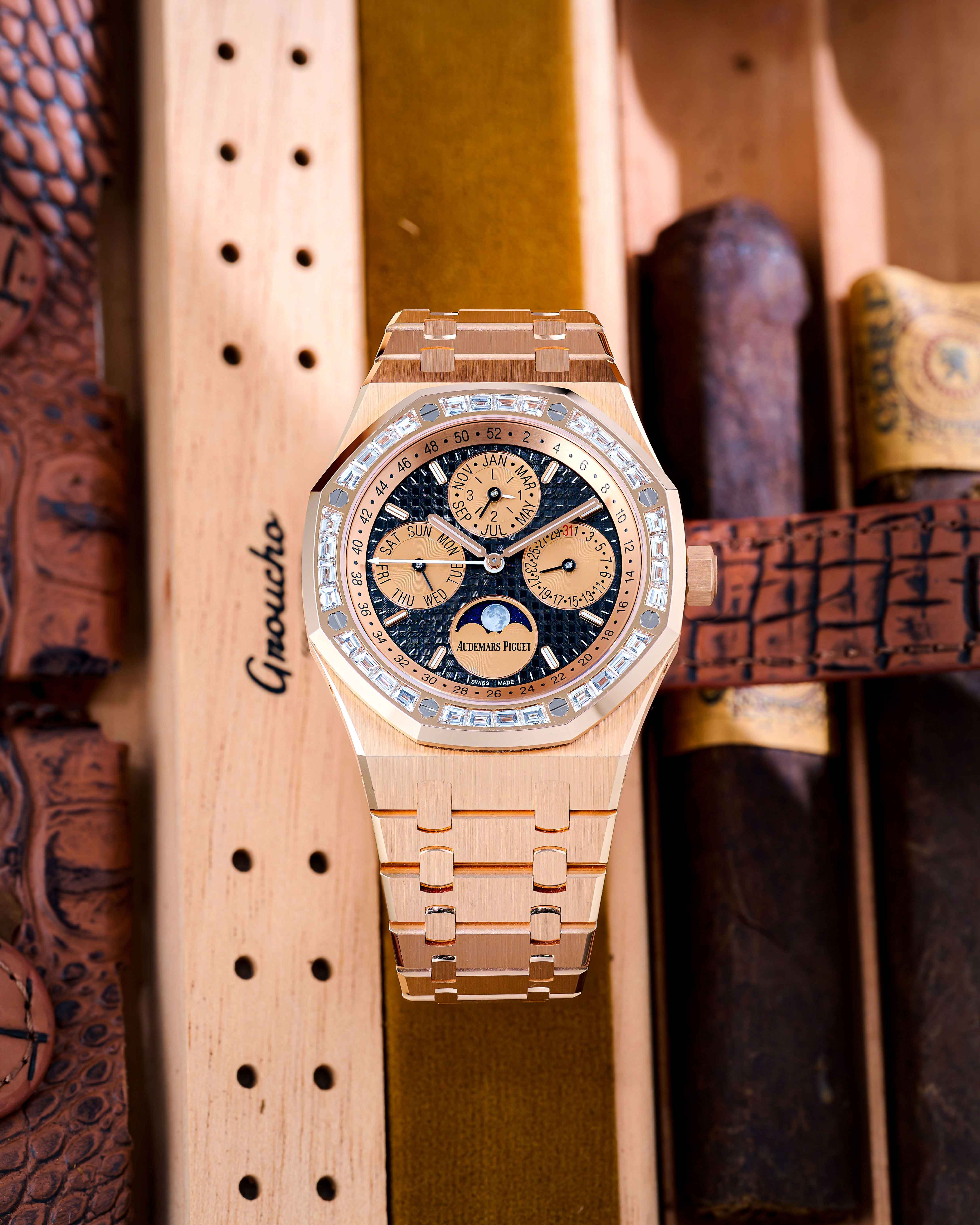 A Rose Gold Timepiece with Four Dials and a Diamond Bezel Lays Inside a Wooden Box Next to Cigars.