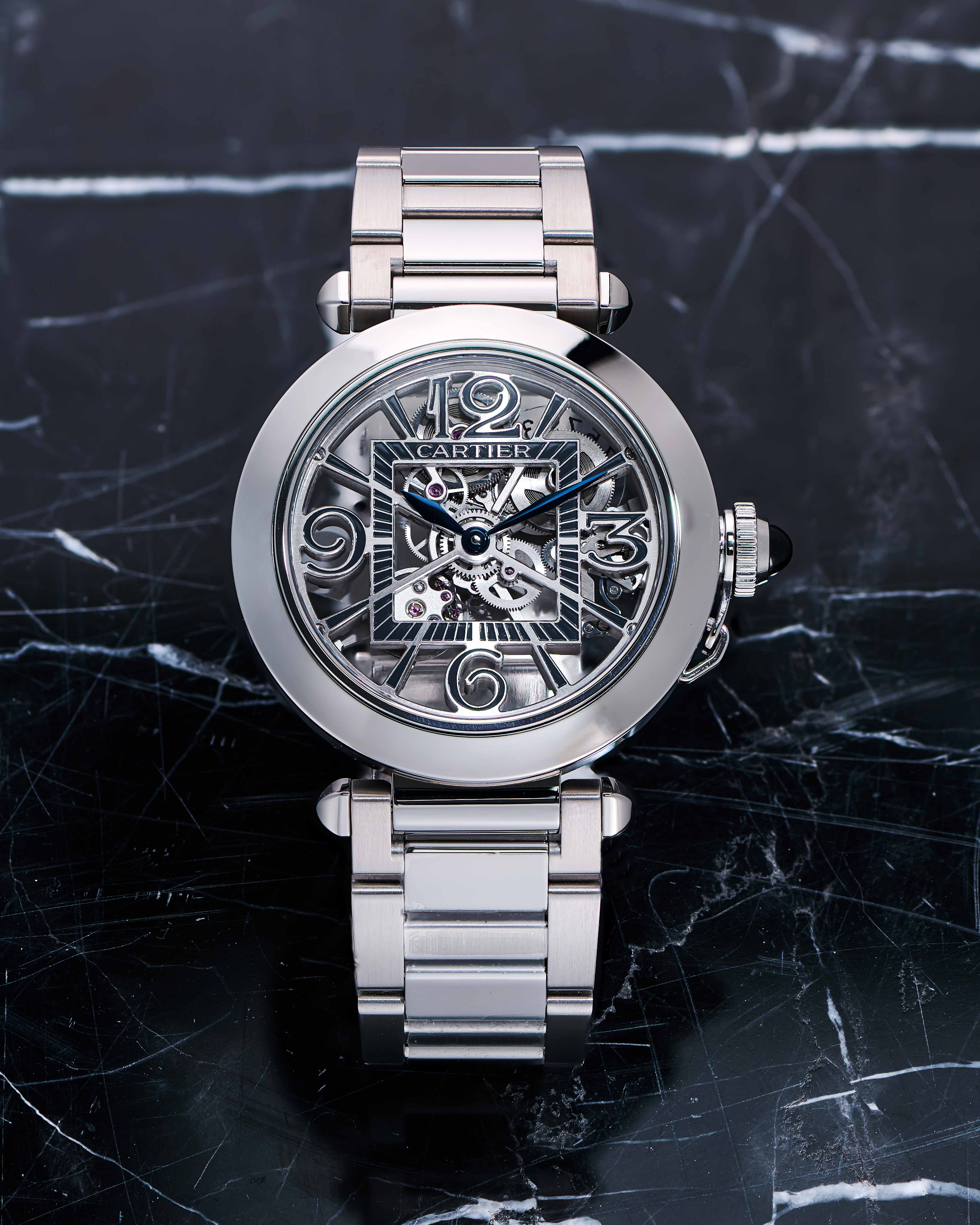 Stainless Steel Timepiece with Skeleton Dial on a Black Marble Tabletop.
