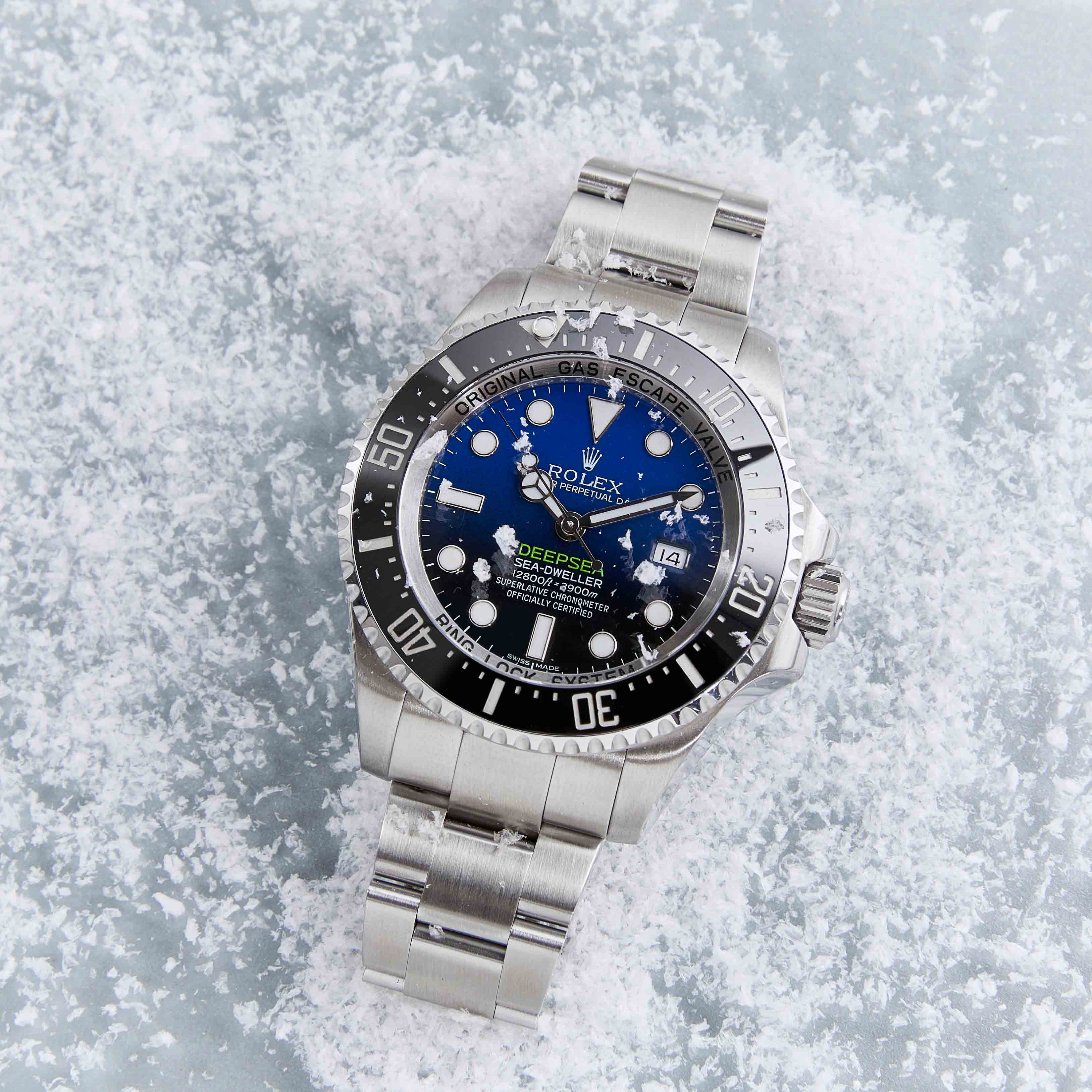Blue Dial with Black Bezel Timepiece on a Sterling Silver Strap Lying on a Snowy Background.