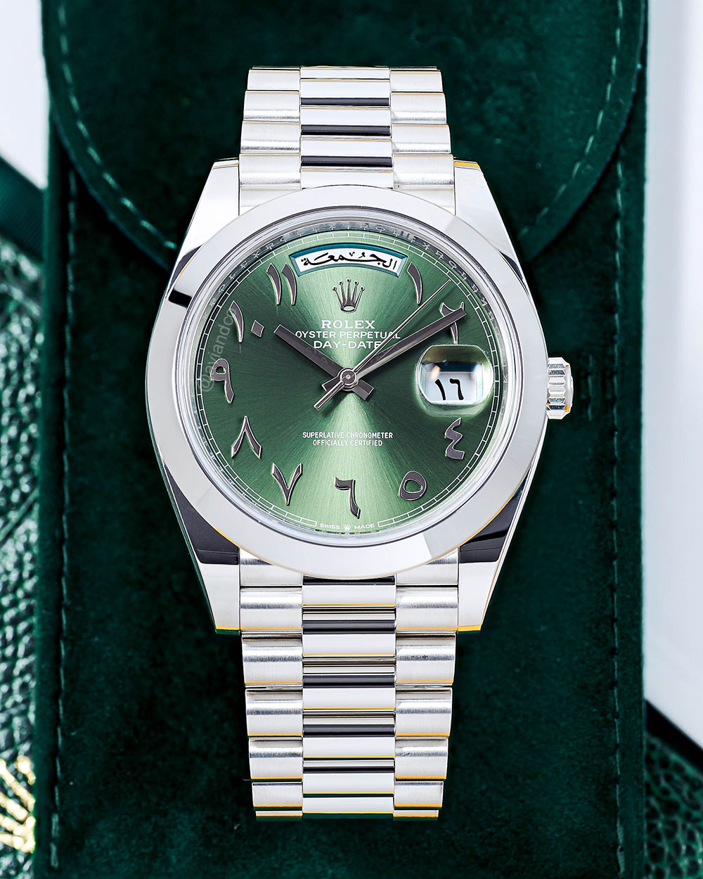 Platinum Rolex Day-Date Timepiece with Arabic Hour Markets Displayed on a C-Ring with a Black Background.