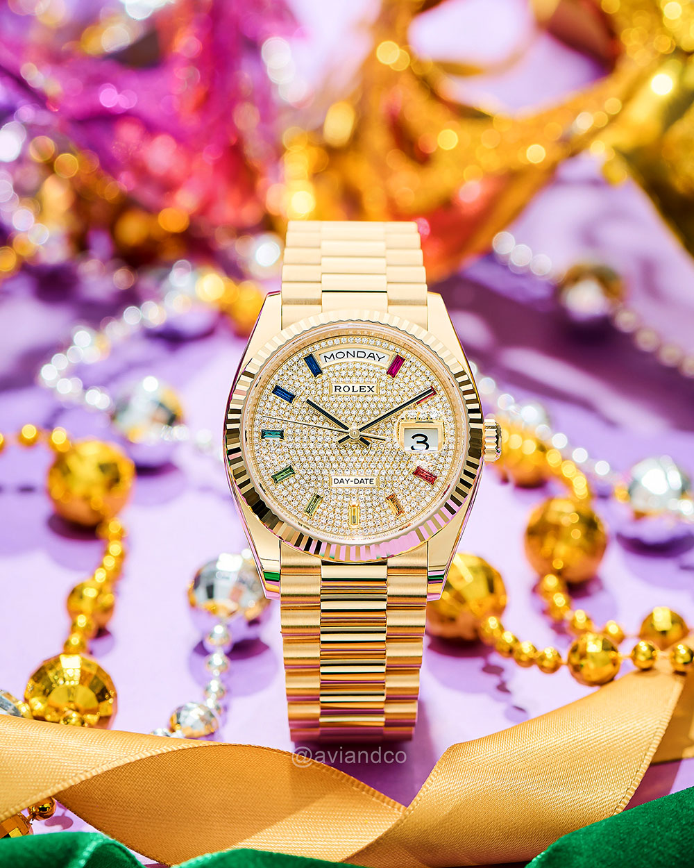 Closeup of 18K Yellow Gold with Rainbow Baguette Pave Dial Timepiece Displayed on a C-Ring.
