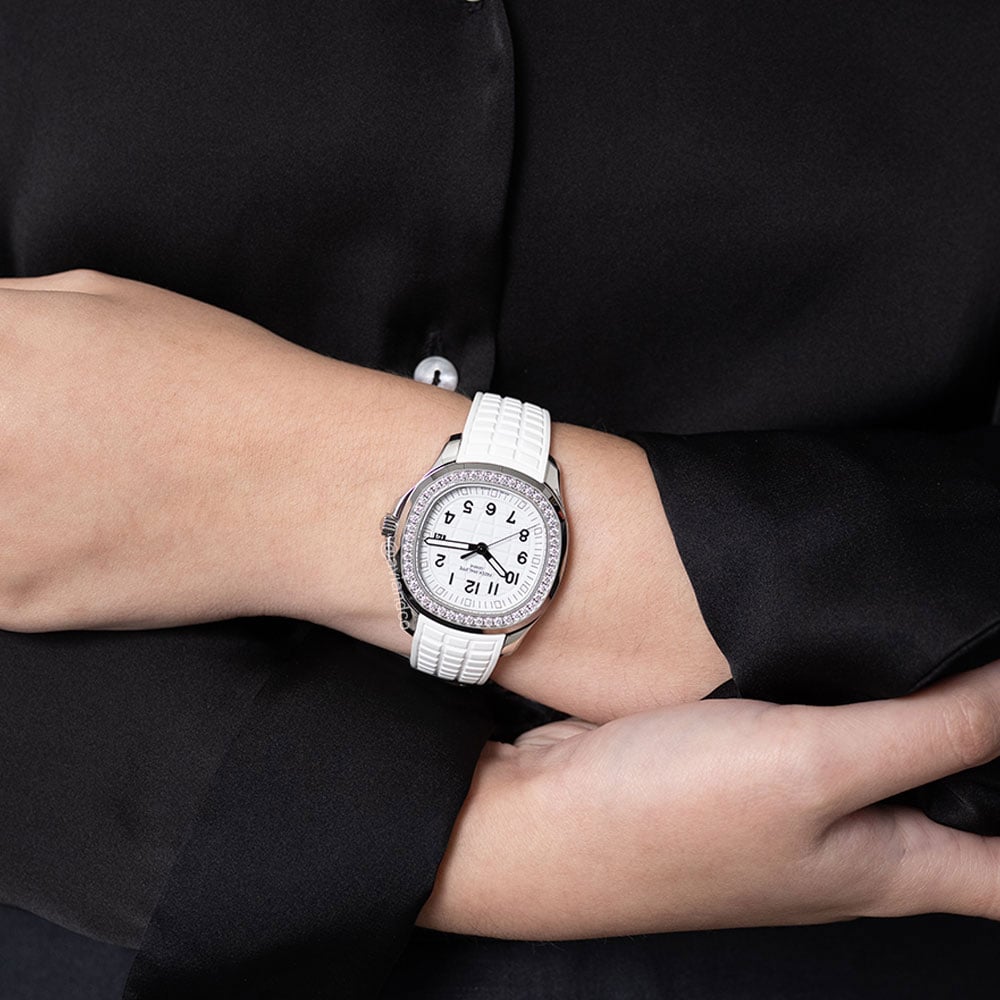 Women's Wrist Wearing 38 mm Patek Philippe Aquanaut with white band, white dial, arabic numerals, diamond bezel, 18K white gold case